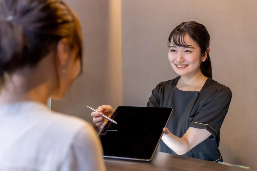 受付でタブレットを案内するスタッフ