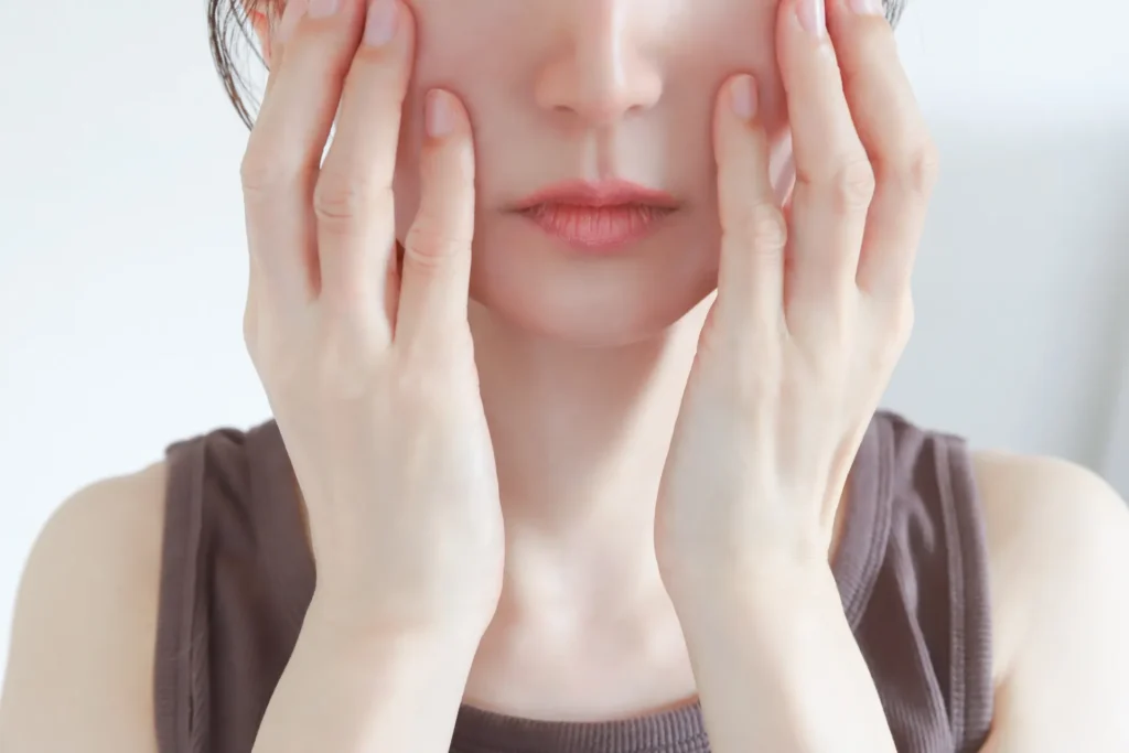 両手で頬に触れる女性(Vビーム治療のイメージ)