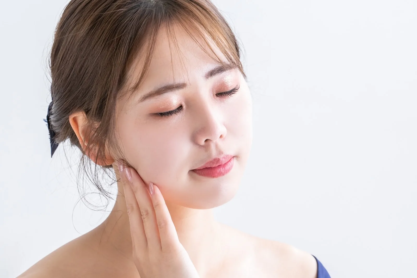 頬に手を当てて目を閉じる女性
