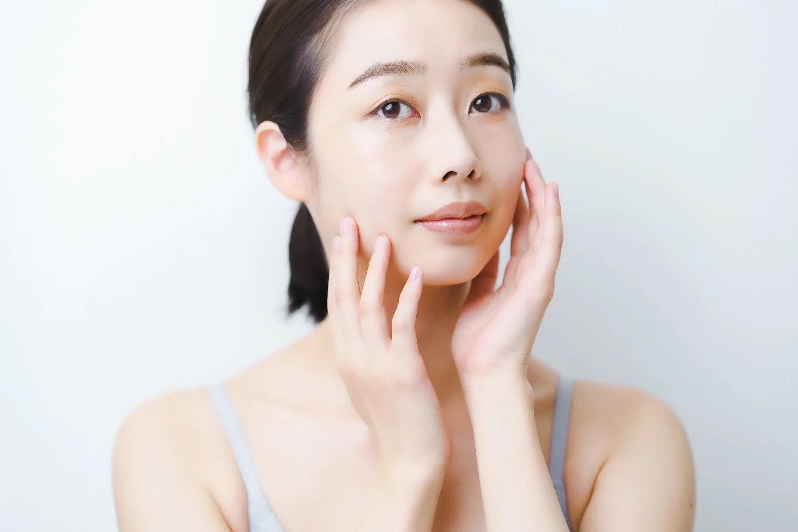 両手で頬に触れる女性