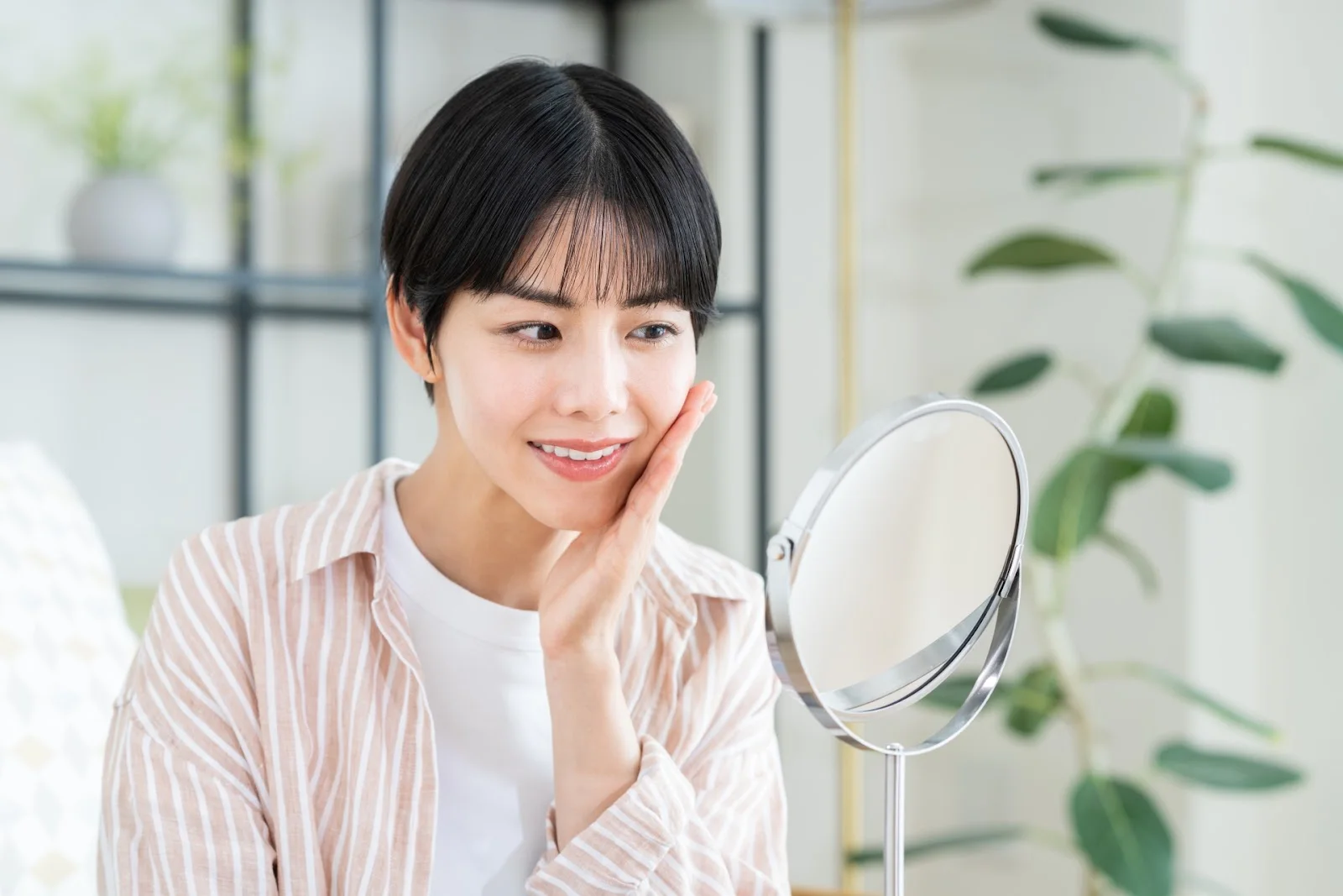 手鏡を見ながら頬に手を当てる女性