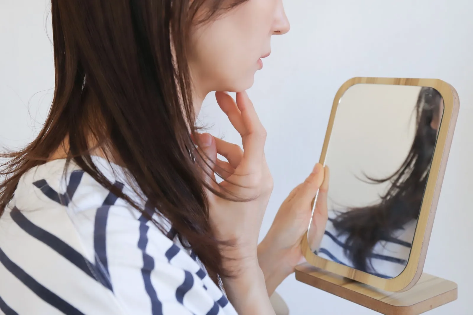 手鏡で自分の肌を確認する女性
