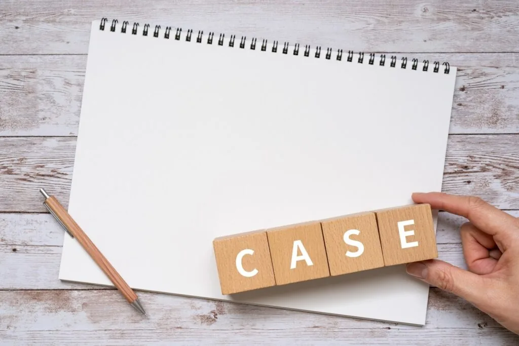 ノートの上に「CASE」と書かれた木製ブロックを並べる手