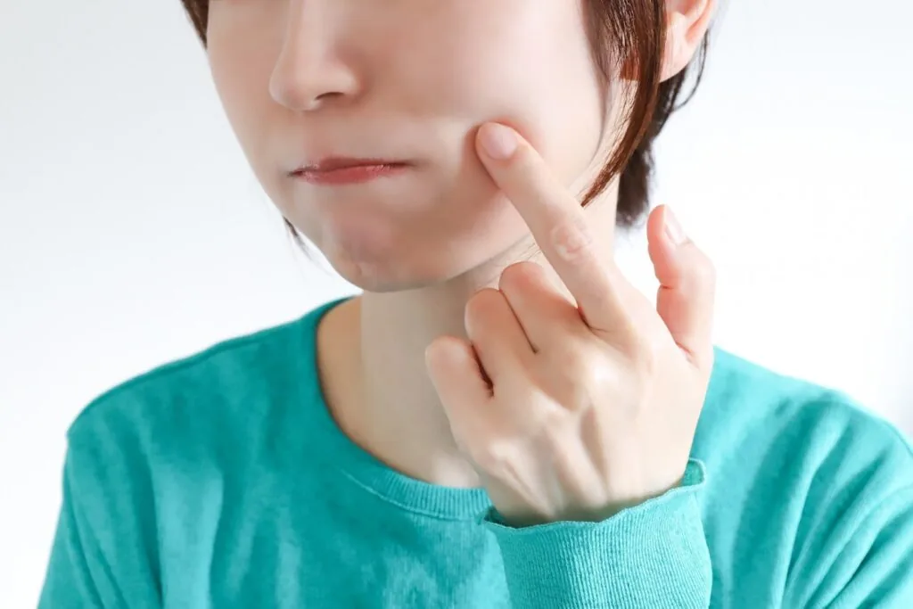 頬に指を当てる女性