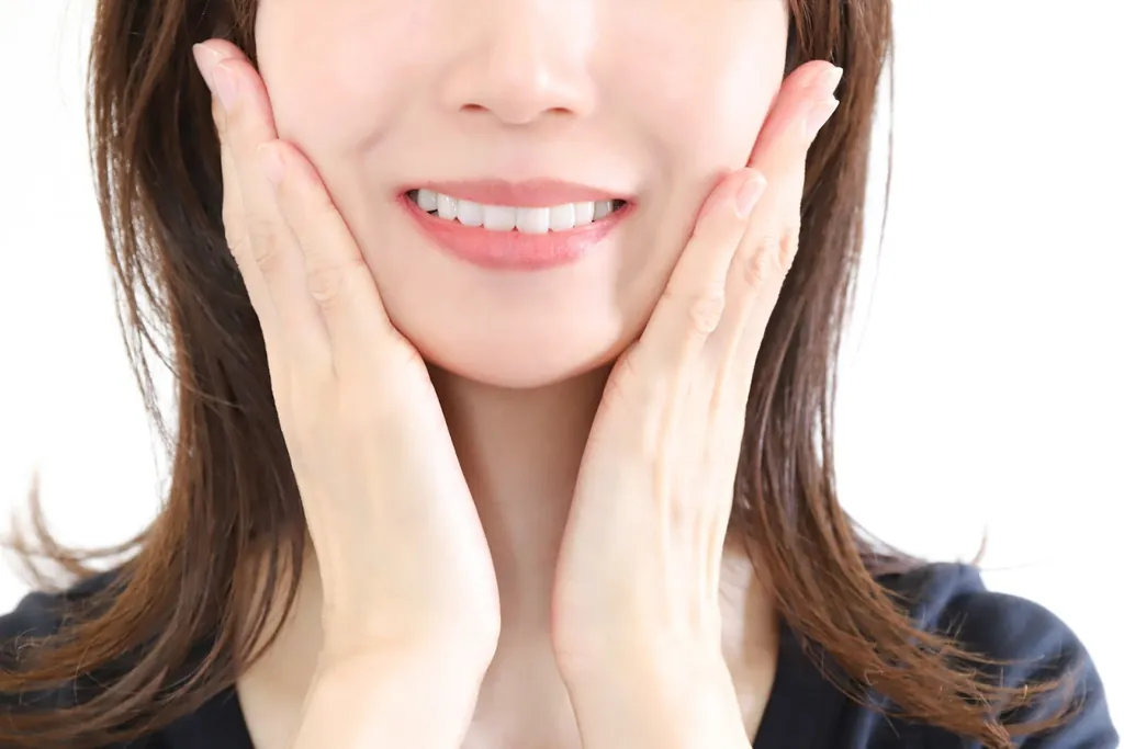 両手で頬を包んでほほえむ女性