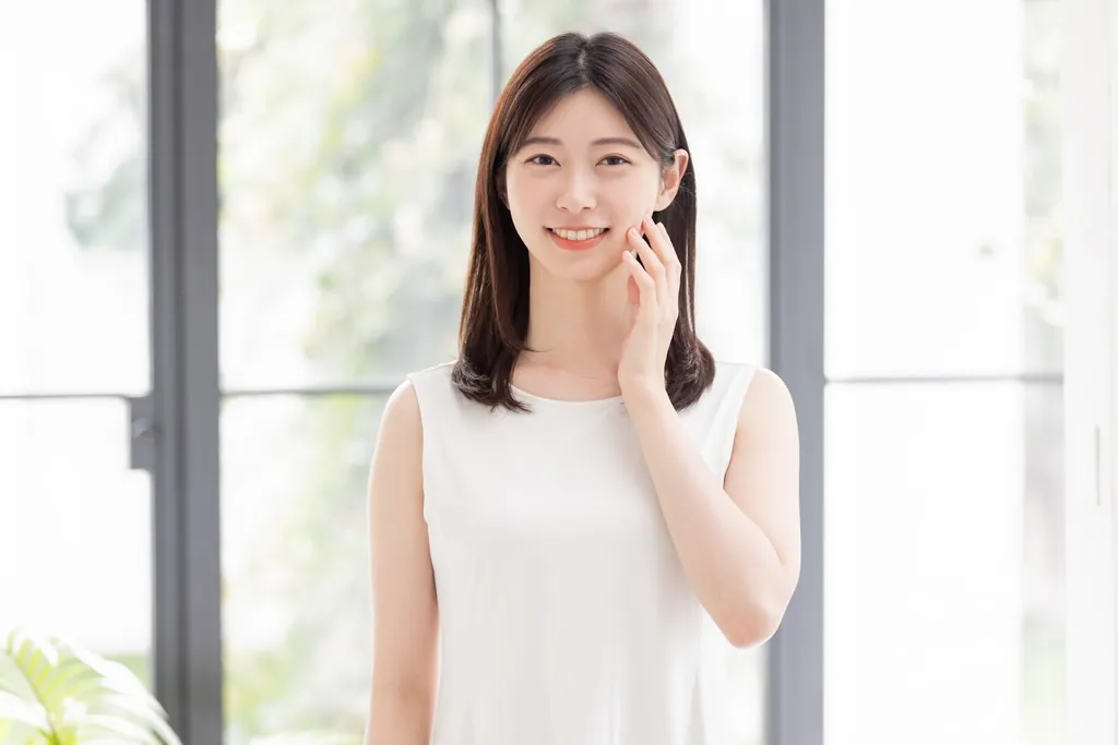 窓辺で頬に手を当てる女性