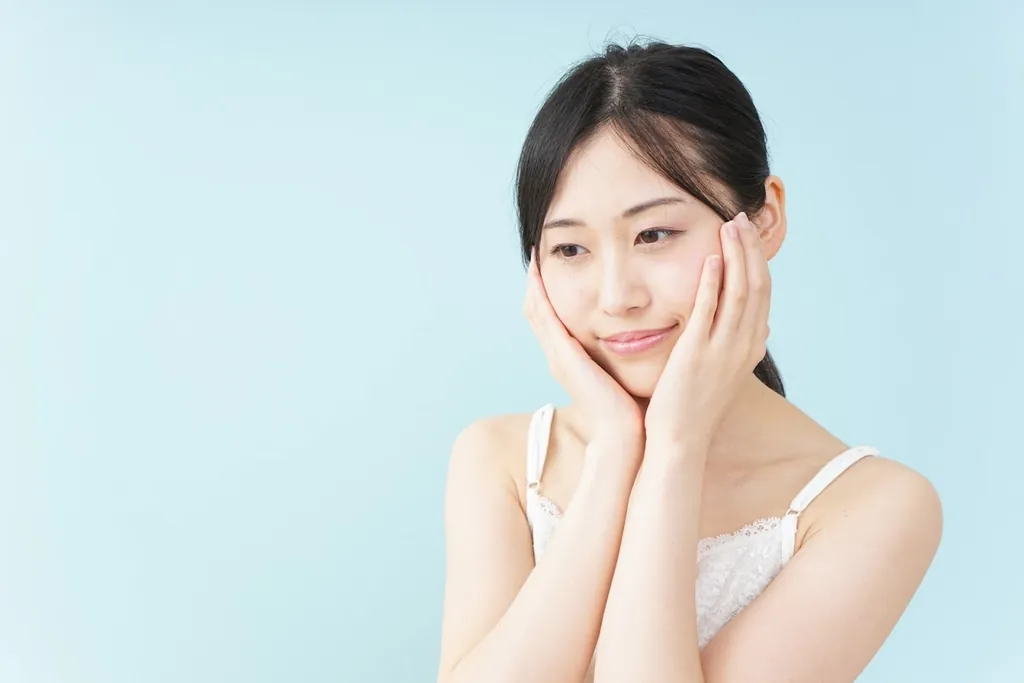 両手を頬に添えてほほえむ女性