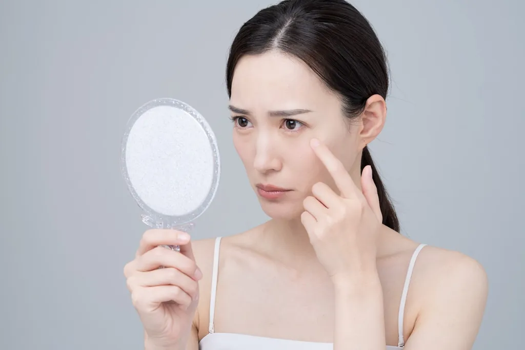 手鏡を見ながら頬に触れる女性