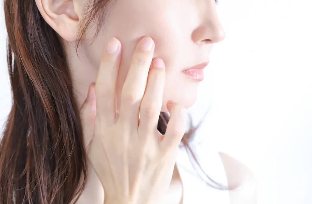 頬に指先で触れる女性の横顔