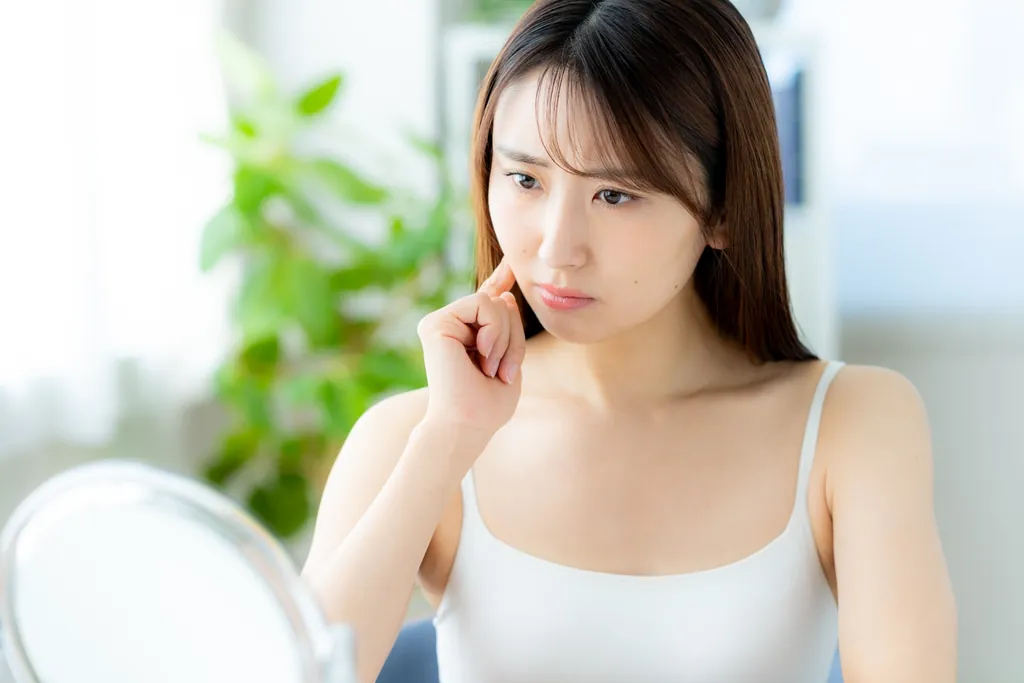 鏡の前で頬に指を当てる女性