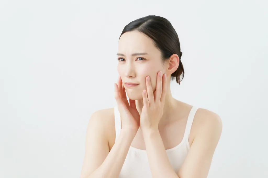 両手で頬を押さえて困った表情の女性
