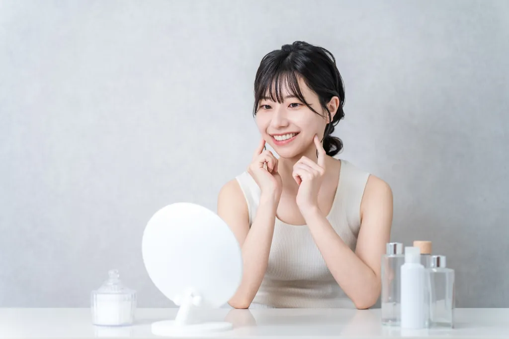 鏡の前で頬に指を当ててほほえむ女性