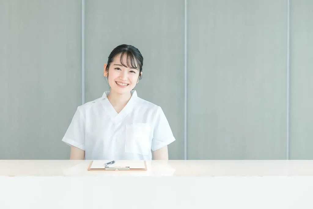 受付カウンターでほほえむ白衣の女性