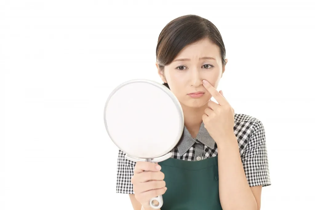手鏡を持って鼻を指さす女性
