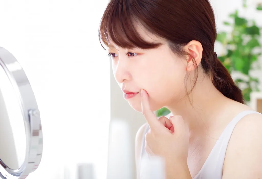 鏡の前で口元に指を当てる女性
