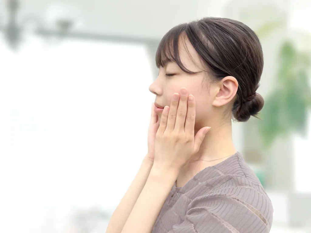 両手で頬を包んで目を閉じる女性