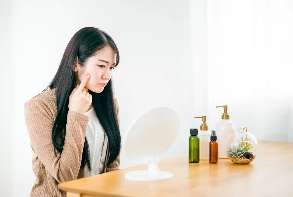 鏡の前で頬に指を当てる女性