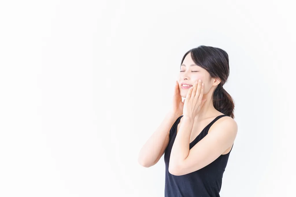 両手で頬を包んでほほえむ女性
