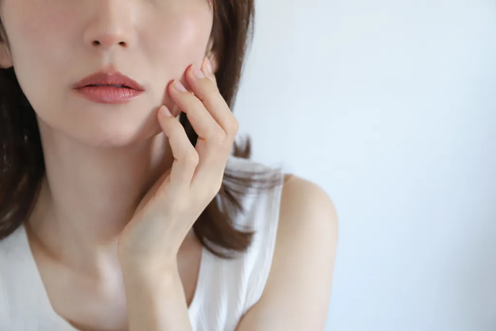 頬に指先を当てる女性の口元