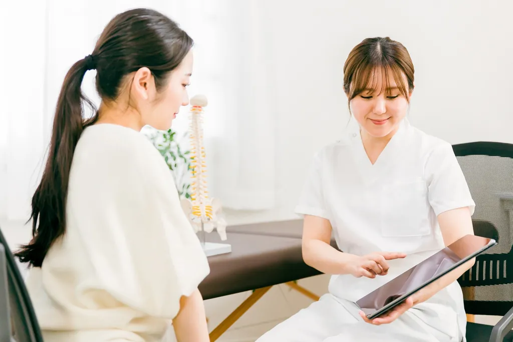 タブレットを持つ白衣の女性と向かい合う女性