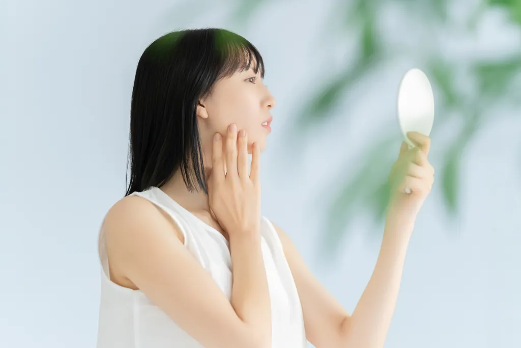 手鏡を持って頬に手を当てる女性