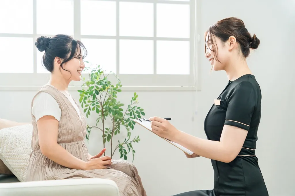 ソファに座る女性の話を聞きながらメモを取るスタッフ