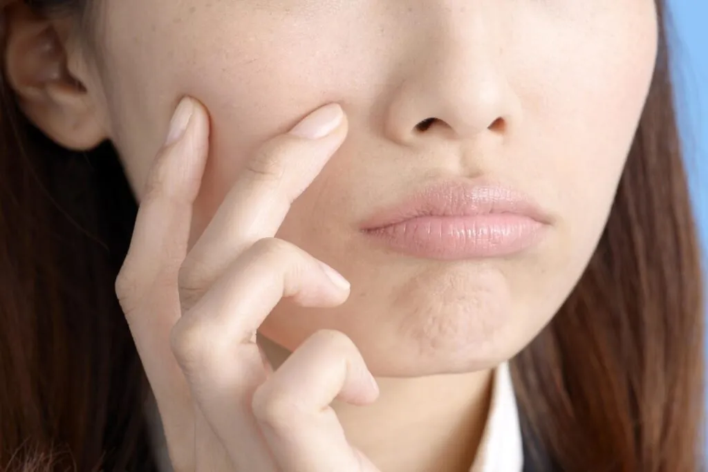 頬に指を当てる女性の口元